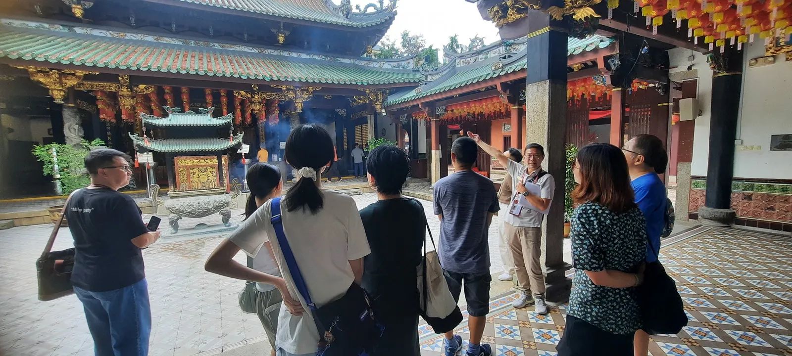 A Serai guide leading a group through a Singapore heritage temple courtyard